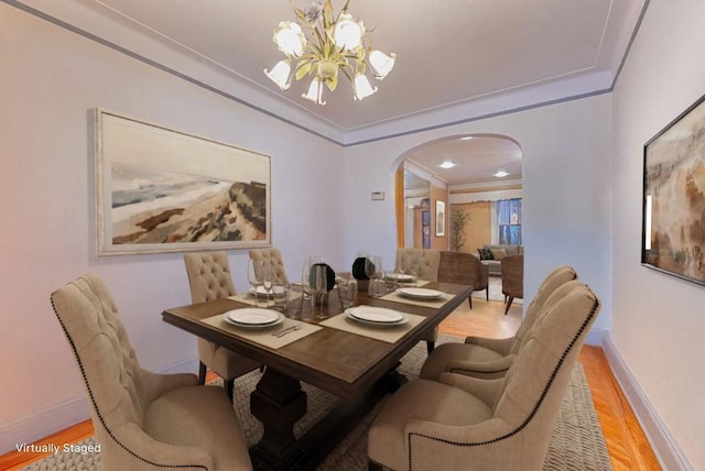 dining area with crown molding, an inviting chandelier, and light hardwood / wood-style floors