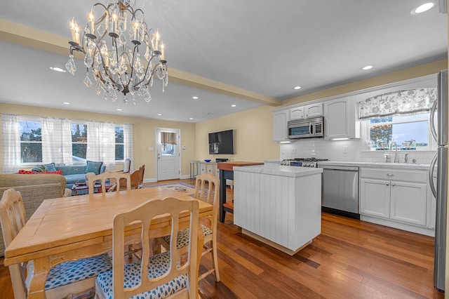 dining room featuring wood-type flooring, sink, and an inviting chandelier