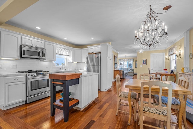 kitchen featuring a wealth of natural light, decorative light fixtures, white cabinets, decorative backsplash, and stainless steel appliances