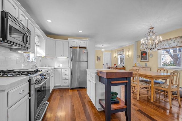 kitchen featuring white cabinetry, appliances with stainless steel finishes, dark hardwood / wood-style floors, and pendant lighting