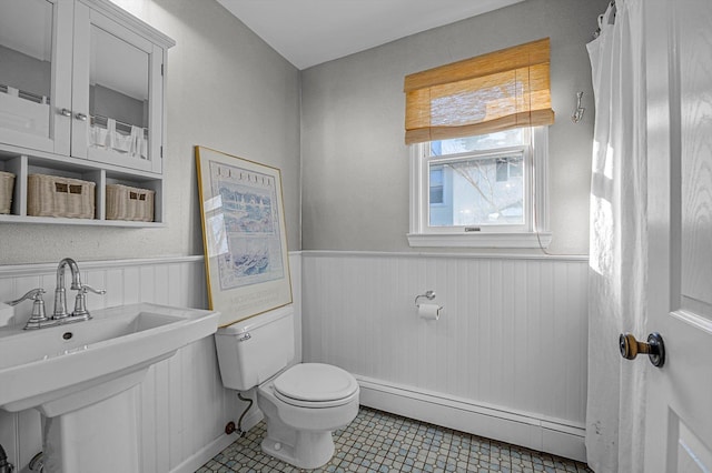 bathroom with a baseboard heating unit, sink, tile patterned floors, and toilet