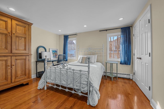 bedroom featuring baseboard heating, multiple windows, and hardwood / wood-style flooring