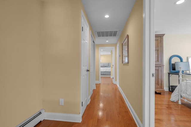 hallway featuring wood-type flooring and a baseboard heating unit