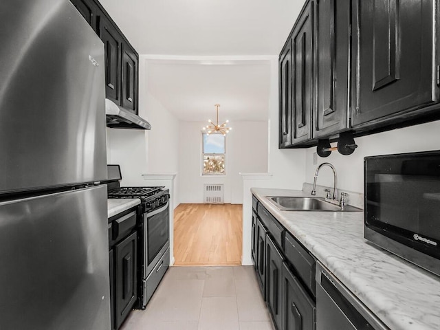 kitchen featuring radiator heating unit, stainless steel appliances, sink, a notable chandelier, and light tile patterned floors