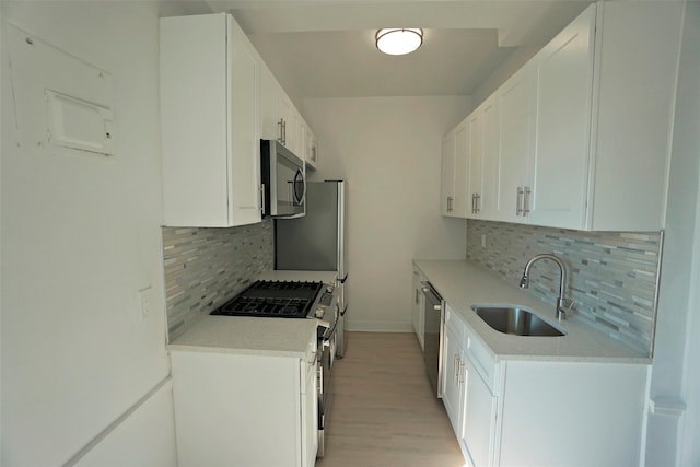 kitchen featuring tasteful backsplash, appliances with stainless steel finishes, sink, and white cabinetry