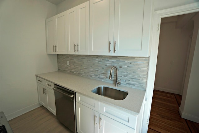 kitchen featuring backsplash, dishwasher, sink, light stone countertops, and white cabinets