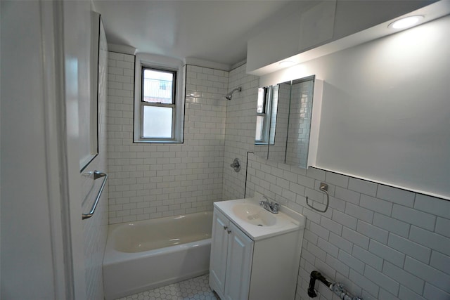 bathroom with tile walls, tile patterned floors, vanity, and tiled shower / bath combo