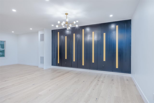 spare room with light hardwood / wood-style flooring and a chandelier