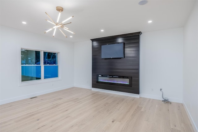 unfurnished living room with a chandelier, a fireplace, and light hardwood / wood-style flooring