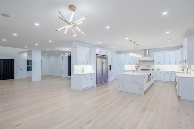 kitchen with a center island, wall chimney exhaust hood, white cabinetry, decorative backsplash, and sink