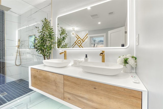 bathroom with a tile shower and vanity