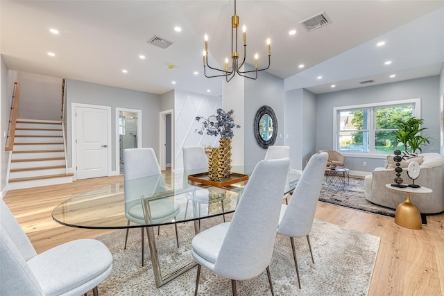 dining area with an inviting chandelier, lofted ceiling, and light hardwood / wood-style floors