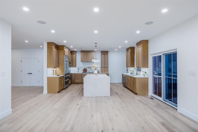 kitchen with light hardwood / wood-style floors, appliances with stainless steel finishes, sink, hanging light fixtures, and a center island