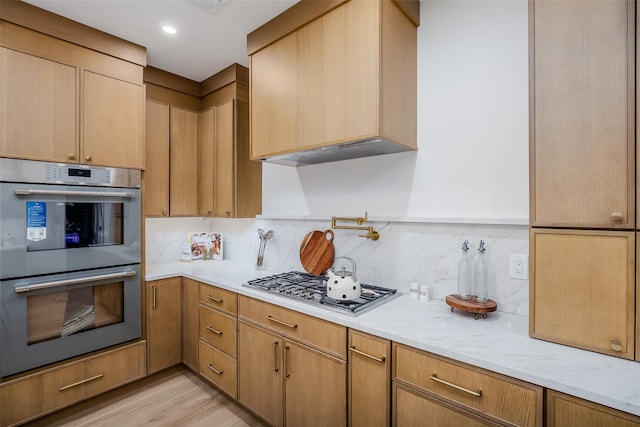 kitchen with decorative backsplash, light hardwood / wood-style flooring, light stone countertops, stainless steel appliances, and light brown cabinetry