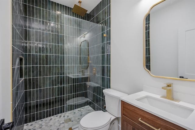 bathroom with toilet, vanity, and tiled shower