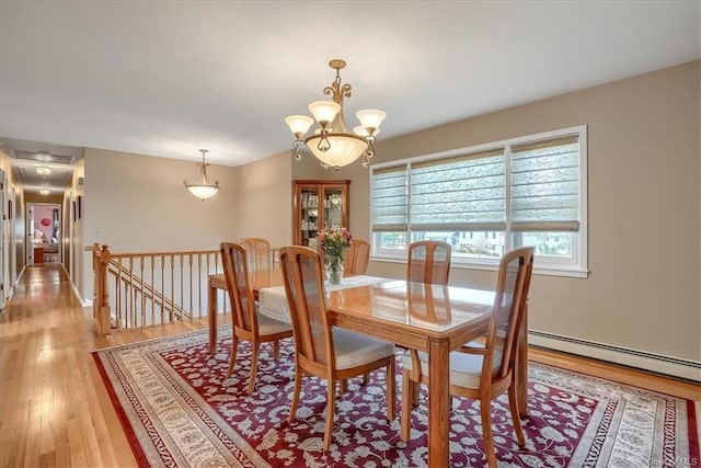 dining area featuring baseboard heating, an inviting chandelier, and light wood-type flooring