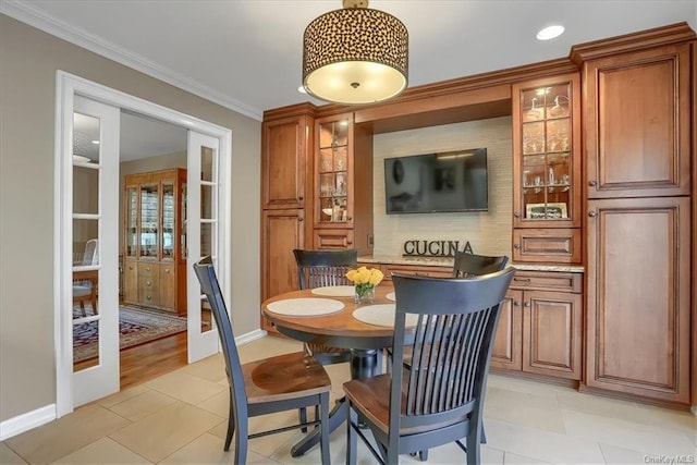 dining space with light tile patterned floors, crown molding, and french doors