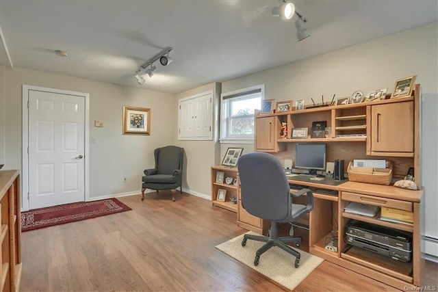 office space featuring rail lighting, baseboard heating, and light wood-type flooring