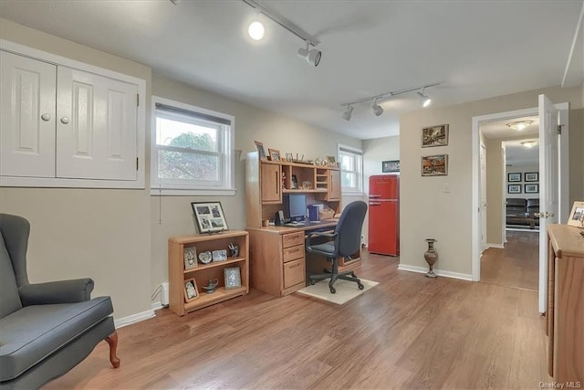 home office featuring rail lighting and light hardwood / wood-style flooring