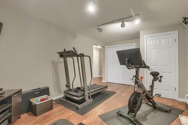 exercise room featuring rail lighting and light hardwood / wood-style floors