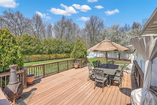 wooden terrace featuring a lawn and a storage unit