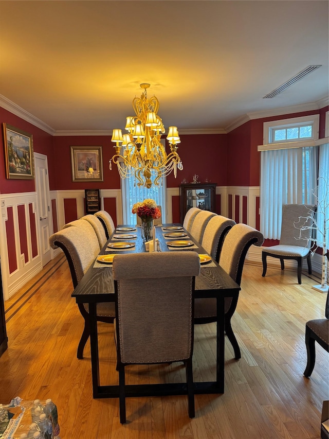 dining area featuring an inviting chandelier, light hardwood / wood-style floors, and crown molding