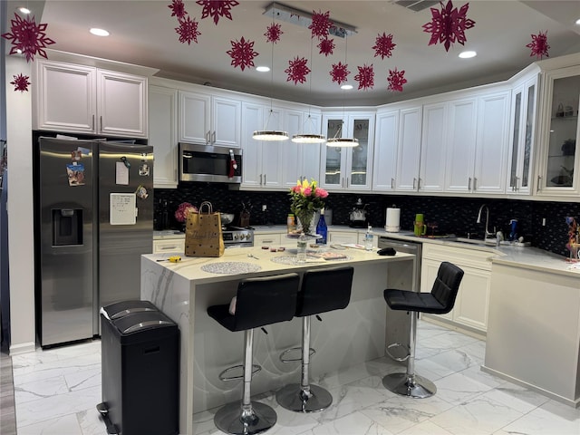 kitchen featuring white cabinetry, a kitchen bar, and appliances with stainless steel finishes