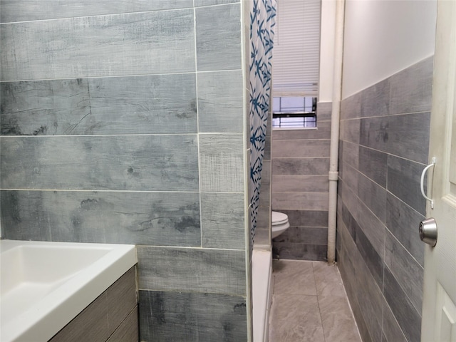 bathroom featuring toilet, tile walls, tile patterned floors, and sink