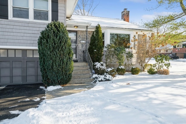 snow covered property entrance with a garage