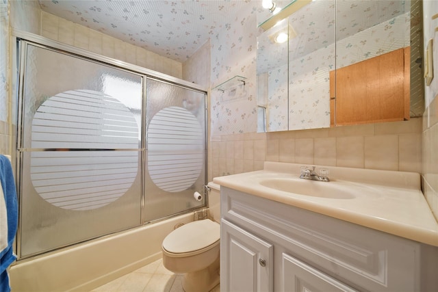 full bathroom featuring tile patterned flooring, tile walls, combined bath / shower with glass door, toilet, and vanity