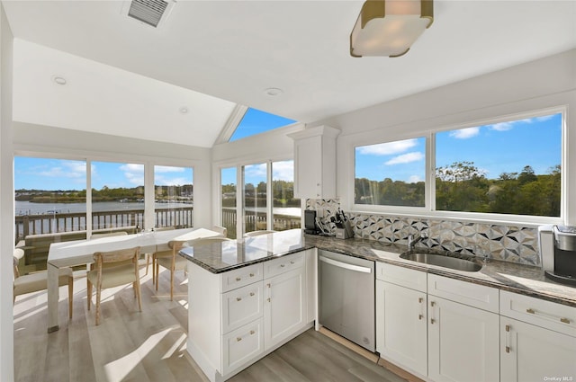 kitchen with tasteful backsplash, dishwasher, sink, white cabinets, and kitchen peninsula