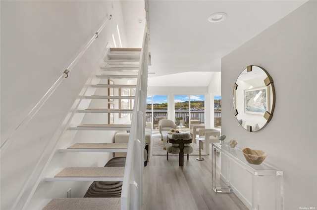 stairs featuring hardwood / wood-style flooring and vaulted ceiling