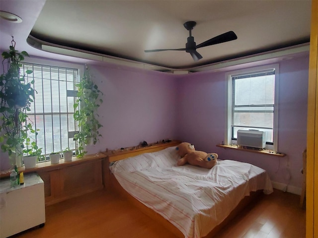 bedroom with a water view, cooling unit, light wood-type flooring, and a tray ceiling