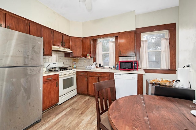 kitchen featuring sink, tasteful backsplash, ceiling fan, white appliances, and light hardwood / wood-style floors