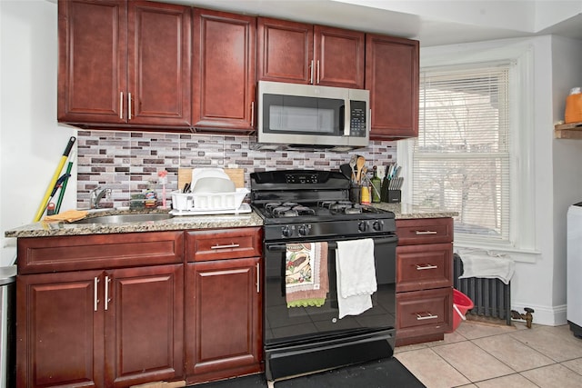 kitchen with sink, black gas range, backsplash, light stone countertops, and light tile patterned flooring