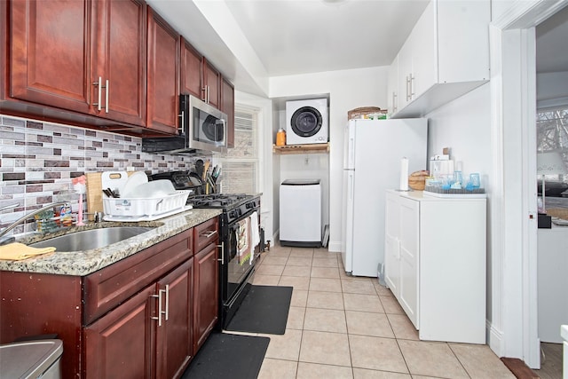 kitchen featuring light tile patterned flooring, tasteful backsplash, sink, white fridge, and black gas range