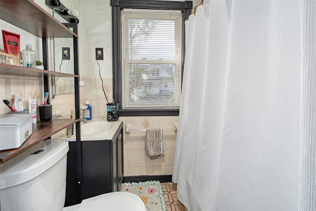 bathroom featuring vanity, tile walls, and toilet