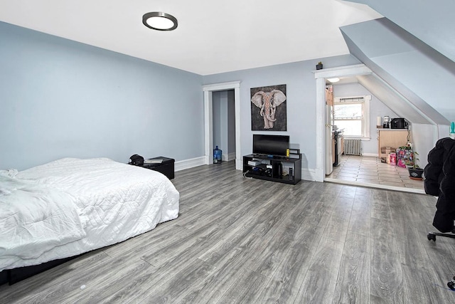 bedroom with lofted ceiling, radiator heating unit, and hardwood / wood-style floors