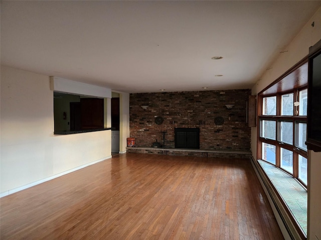 unfurnished living room featuring a baseboard heating unit, a fireplace, and hardwood / wood-style floors