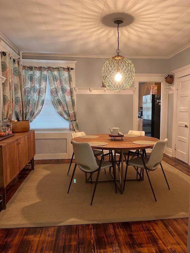 dining room with crown molding, radiator heating unit, and hardwood / wood-style floors