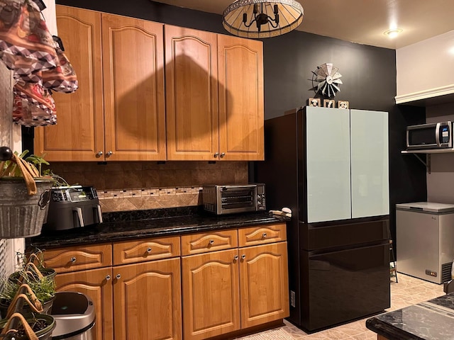 kitchen featuring appliances with stainless steel finishes, backsplash, and dark stone counters