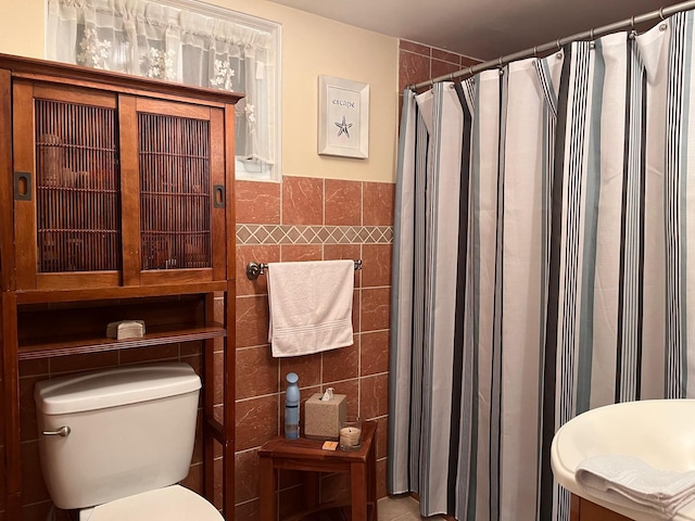 bathroom with toilet, tile walls, and a shower with curtain