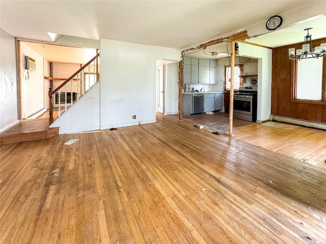 unfurnished living room with a baseboard radiator, hardwood / wood-style floors, and a wall mounted air conditioner