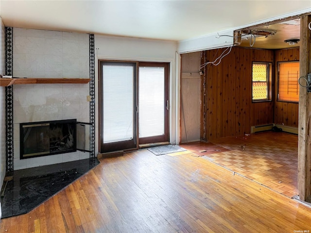 unfurnished living room with wood walls, crown molding, hardwood / wood-style flooring, and a tile fireplace