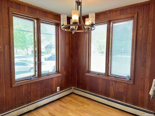 unfurnished dining area with a baseboard radiator, wood walls, and an inviting chandelier