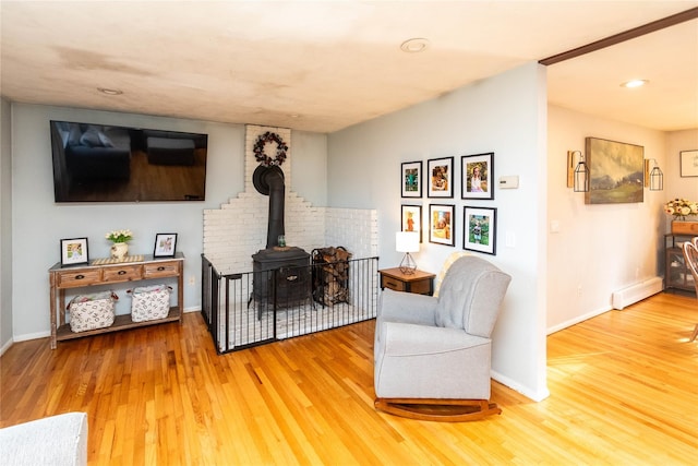 living room with a wood stove, hardwood / wood-style floors, and a baseboard radiator