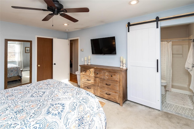 carpeted bedroom featuring ceiling fan, a barn door, and connected bathroom