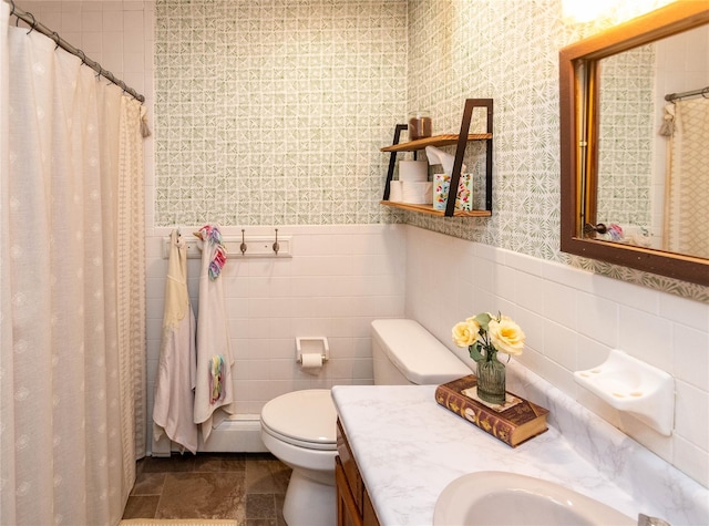 bathroom with toilet, tile walls, vanity, and curtained shower