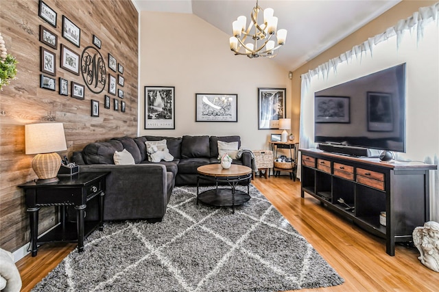 living area featuring an inviting chandelier, wood finished floors, wood walls, and vaulted ceiling