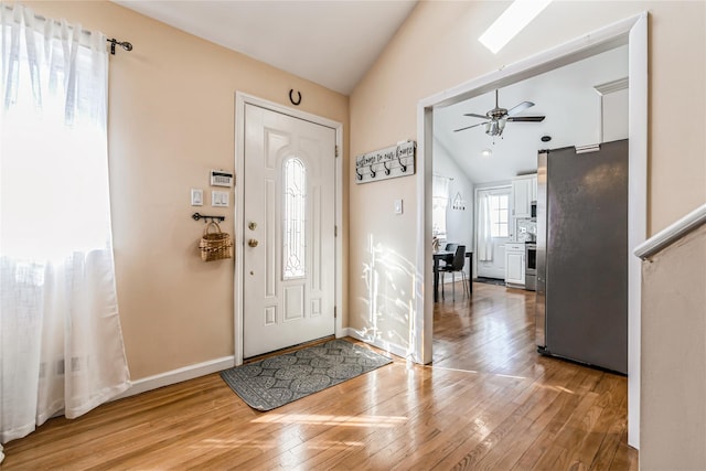 entryway with baseboards, light wood finished floors, a ceiling fan, and vaulted ceiling